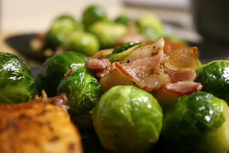 Close-up of glossy pan-fried Brussels sprouts tossed with pieces of crisp bacon