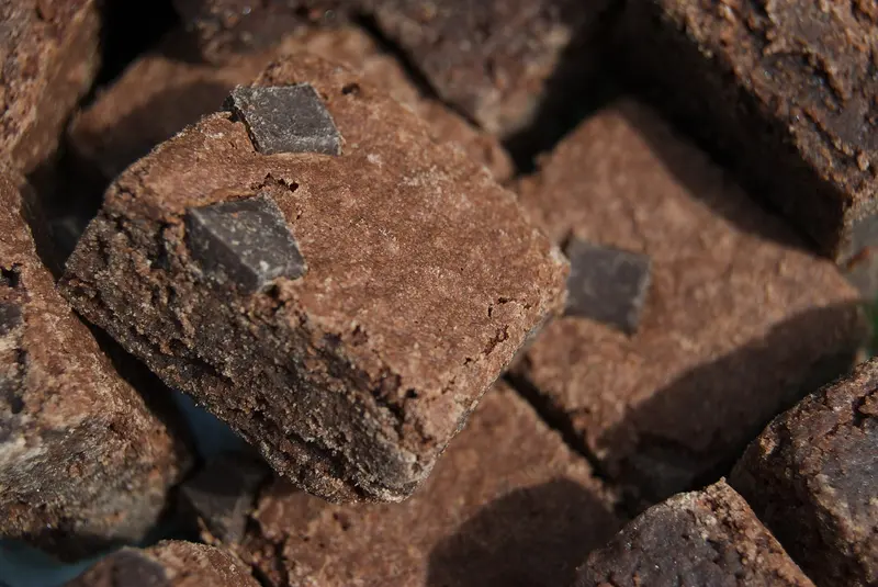 Close-up of stacked square chocolate brownies with crackly tops and chunks of dark chocolate