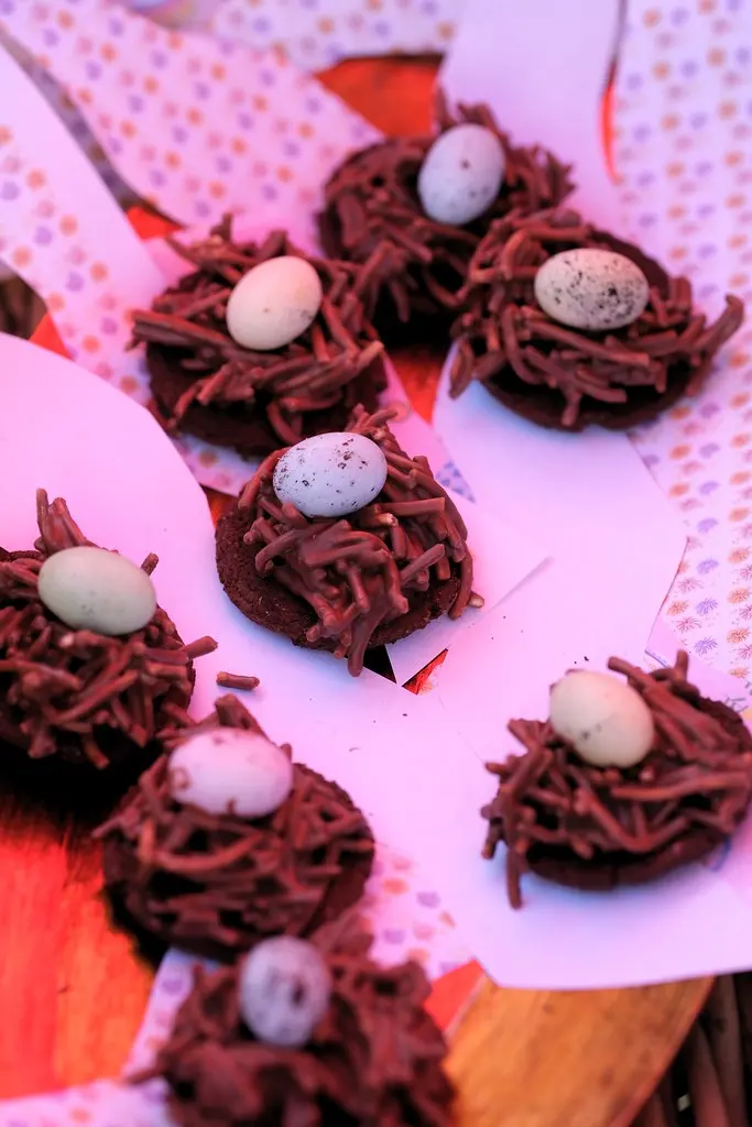 Chocolate Easter nests topped with speckled pastel mini eggs on pink paper