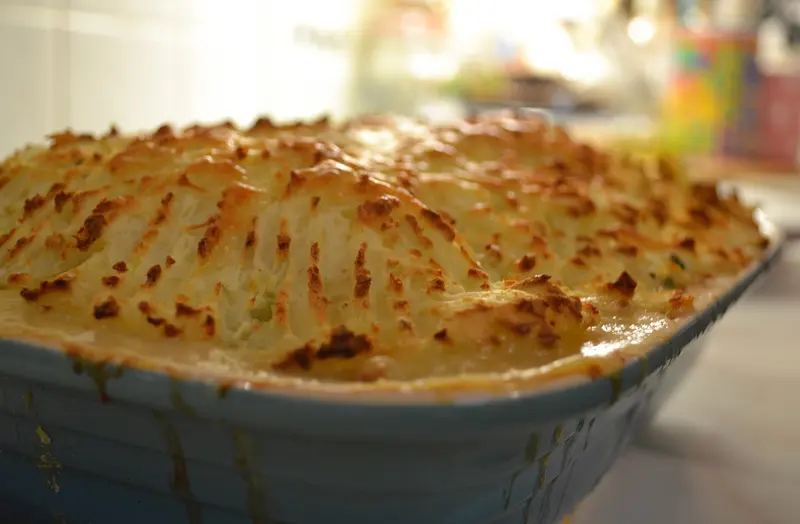 Fish pie in a baking dish with a golden, forked mashed-potato topping