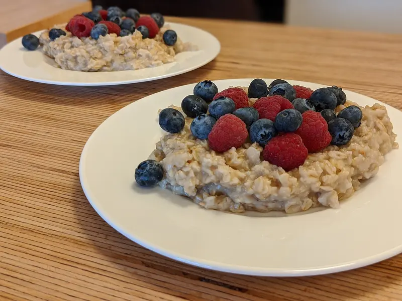 Plate of porridge oats topped with fresh raspberries and blueberries on a wooden table