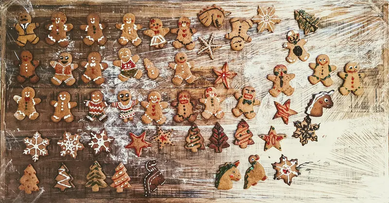 Rows of iced gingerbread biscuits shaped as people, stars and Christmas trees on a table