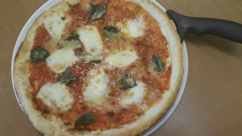 Homemade margherita pizza with tomato sauce, melted mozzarella and basil leaves, seen from above