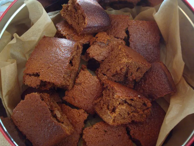 Chunks of dark, moist Yorkshire parkin piled in a paper-lined tin